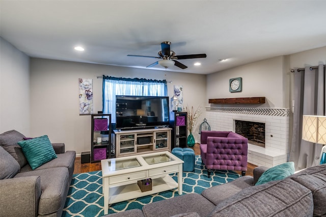 living room featuring ceiling fan, a fireplace, and dark hardwood / wood-style floors