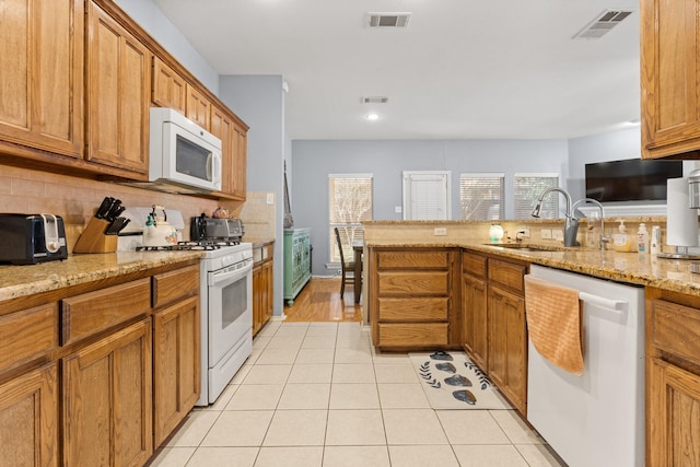 kitchen with light stone countertops, sink, white appliances, and decorative backsplash