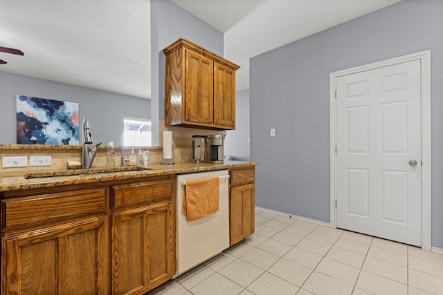 kitchen featuring dishwasher, sink, light stone countertops, and light tile patterned floors