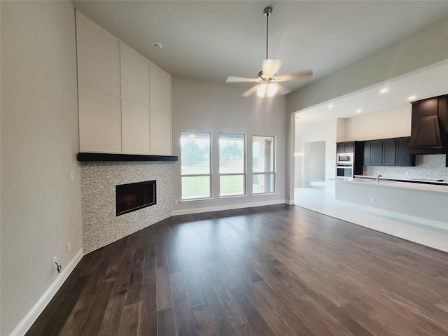 unfurnished living room featuring dark wood-type flooring and ceiling fan