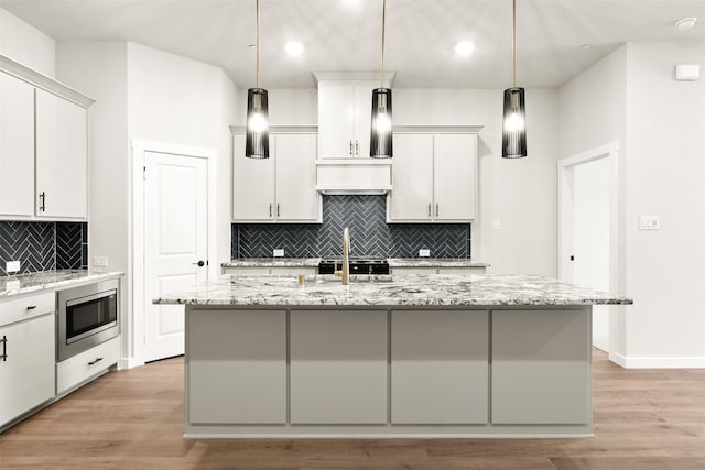 604 Tall Grass Trl, Wylie, TX 75098 - kitchen with stainless steel microwave, tasteful backsplash, light wood-style floors, an island with sink, and recessed lighting