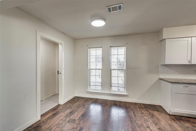 unfurnished dining area with dark hardwood / wood-style flooring and a textured ceiling