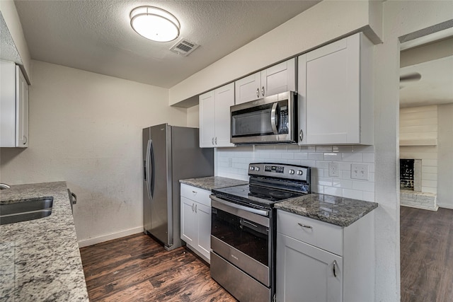 kitchen with sink, white cabinets, light stone counters, stainless steel appliances, and a textured ceiling