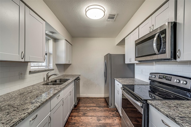 kitchen featuring white cabinetry, appliances with stainless steel finishes, sink, and light stone counters