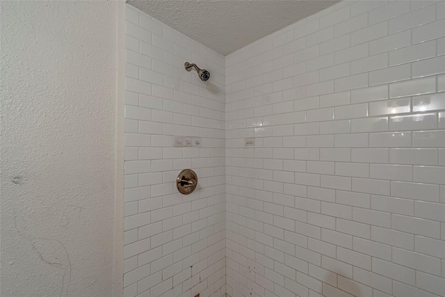 bathroom featuring a textured ceiling and tiled shower