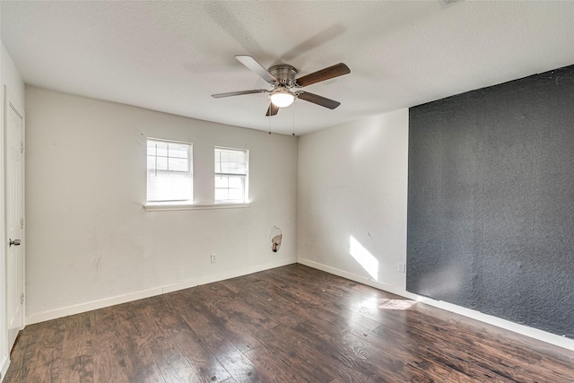 spare room featuring dark wood-type flooring, ceiling fan, and a textured ceiling