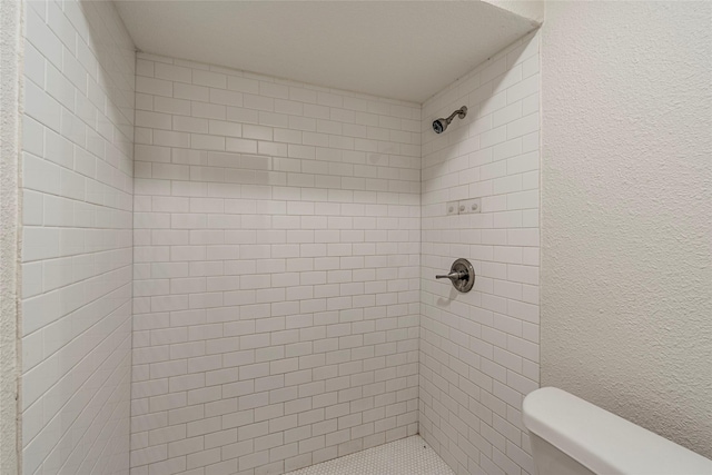 bathroom with tiled shower and toilet