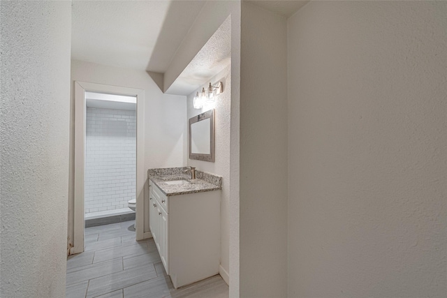 bathroom with vanity, toilet, a textured ceiling, and a shower