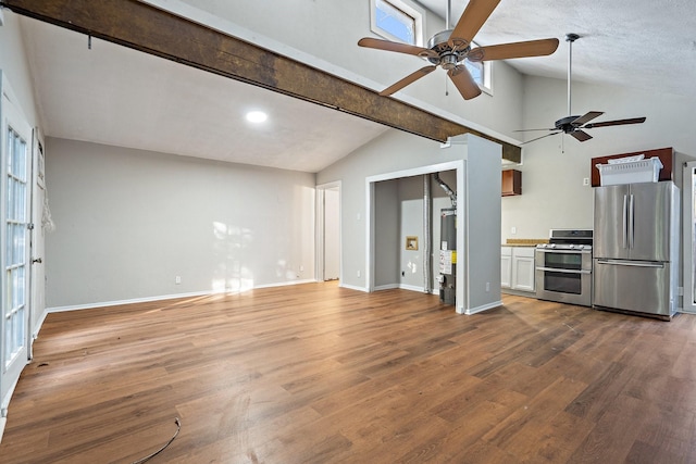 kitchen with water heater, appliances with stainless steel finishes, hardwood / wood-style floors, white cabinets, and vaulted ceiling