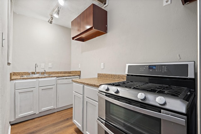 kitchen with sink, rail lighting, dishwasher, white cabinetry, and range with two ovens