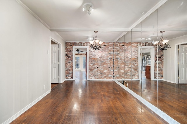 unfurnished dining area with dark wood-type flooring, ornamental molding, brick wall, and a chandelier