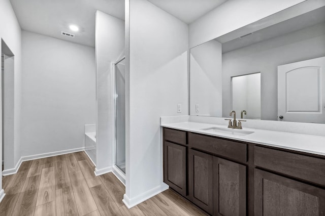 bathroom with wood-type flooring, independent shower and bath, and vanity