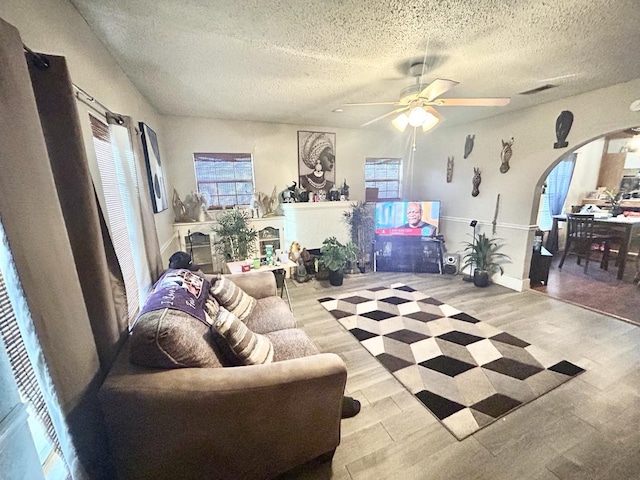 living room featuring ceiling fan, a textured ceiling, and light hardwood / wood-style flooring