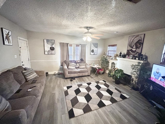 living room with ceiling fan, wood-type flooring, and a textured ceiling