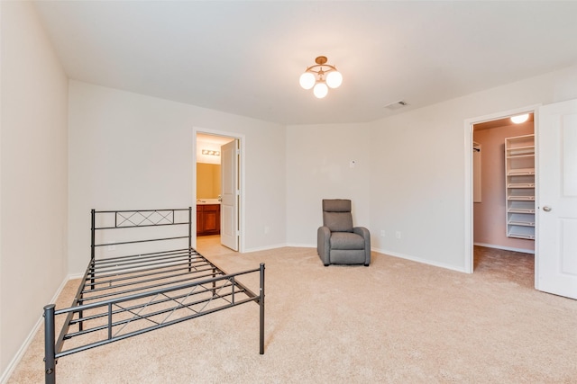 bedroom with ensuite bath, a spacious closet, light carpet, and a closet