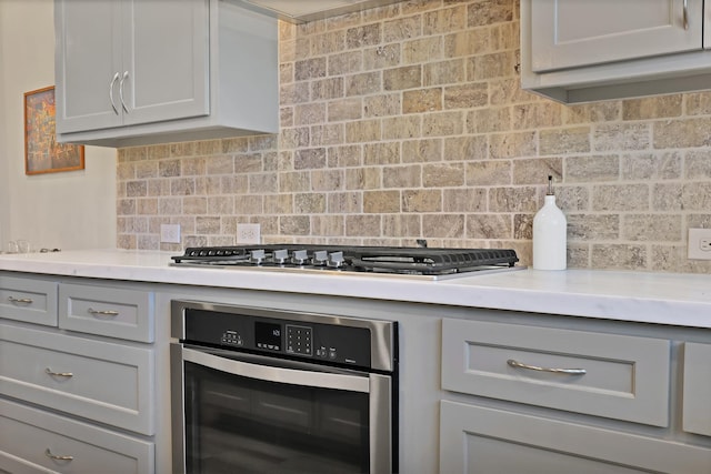 kitchen featuring backsplash, gray cabinets, and appliances with stainless steel finishes