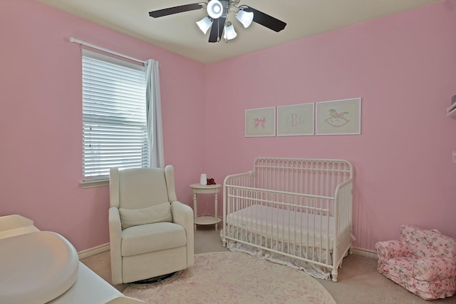 carpeted bedroom featuring ceiling fan, multiple windows, and a crib