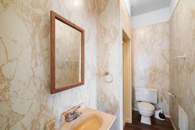 bathroom with wood-type flooring, toilet, and sink