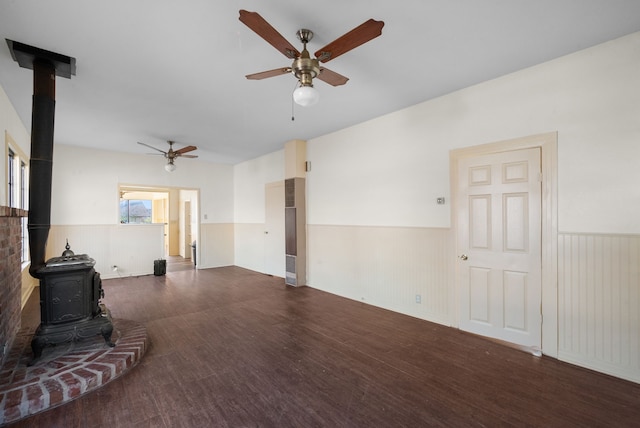 living room with a wood stove, dark wood-type flooring, and ceiling fan