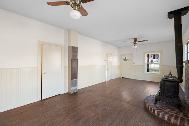 living room featuring dark wood-type flooring, ceiling fan, and a wood stove