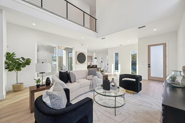 living room with a towering ceiling and light wood-type flooring