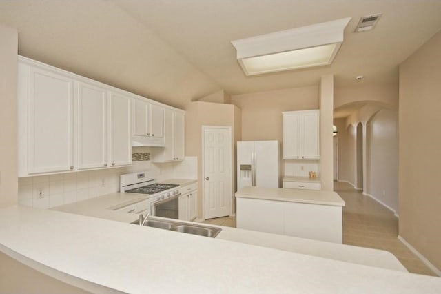 kitchen with white appliances, kitchen peninsula, and white cabinets