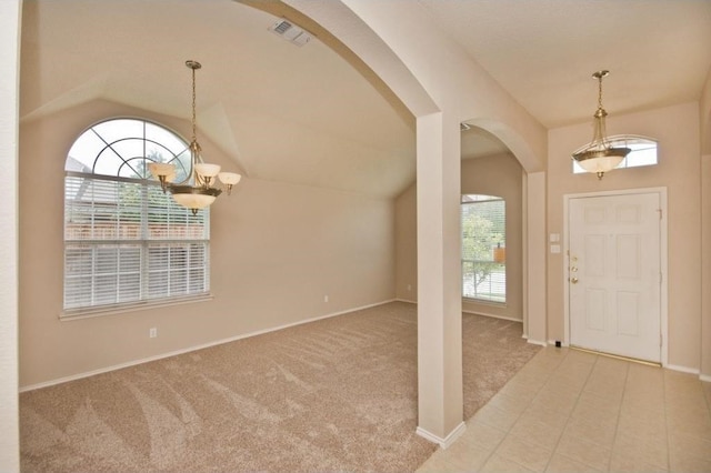 carpeted entrance foyer with vaulted ceiling, plenty of natural light, and an inviting chandelier