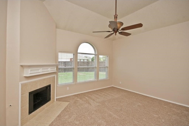 unfurnished living room with light colored carpet, vaulted ceiling, a tile fireplace, and ceiling fan