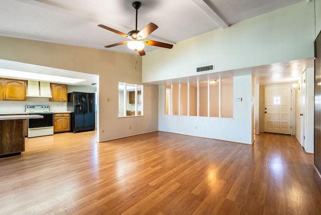 unfurnished living room with ceiling fan, beam ceiling, and light hardwood / wood-style floors