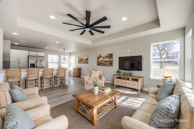 living room featuring ceiling fan, a raised ceiling, and hardwood / wood-style floors