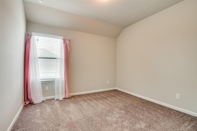 empty room featuring vaulted ceiling and carpet flooring