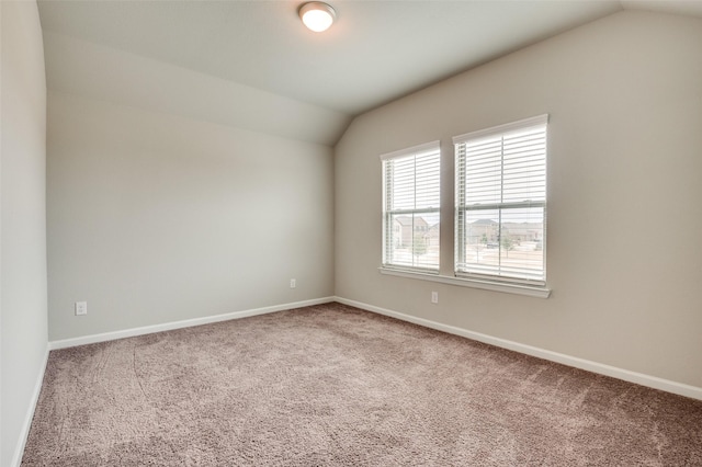 carpeted empty room featuring vaulted ceiling