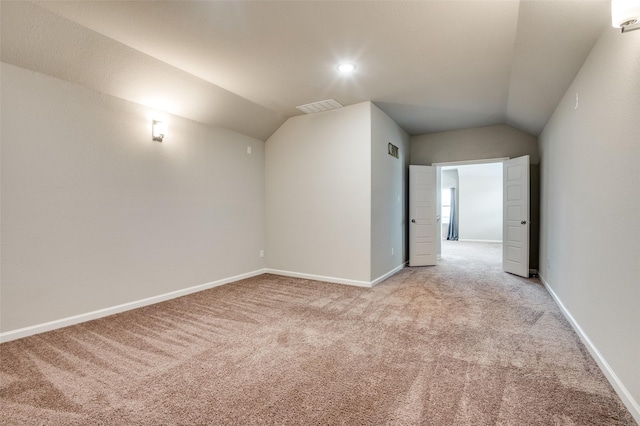 bonus room with lofted ceiling and light colored carpet