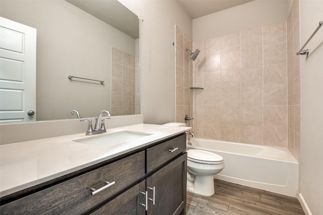 full bathroom with tiled shower / bath combo, vanity, hardwood / wood-style floors, and toilet