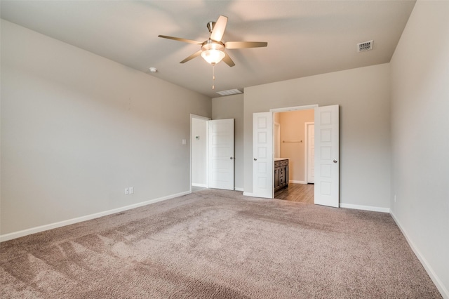 unfurnished bedroom featuring dark carpet, ensuite bath, and ceiling fan