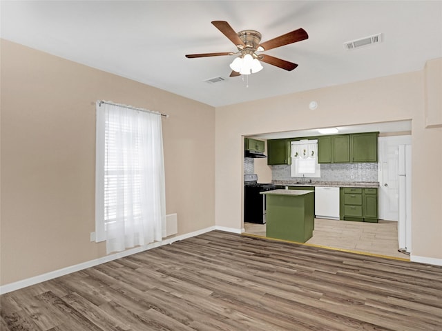 kitchen with tasteful backsplash, sink, hardwood / wood-style flooring, green cabinetry, and white appliances