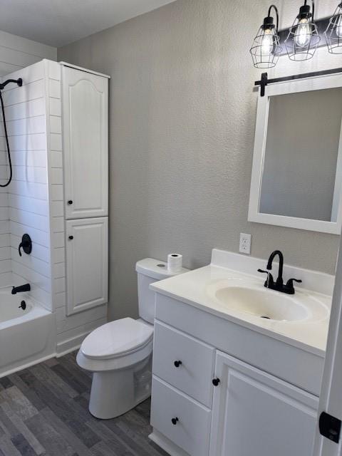 full bathroom featuring tiled shower / bath, hardwood / wood-style floors, vanity, and toilet