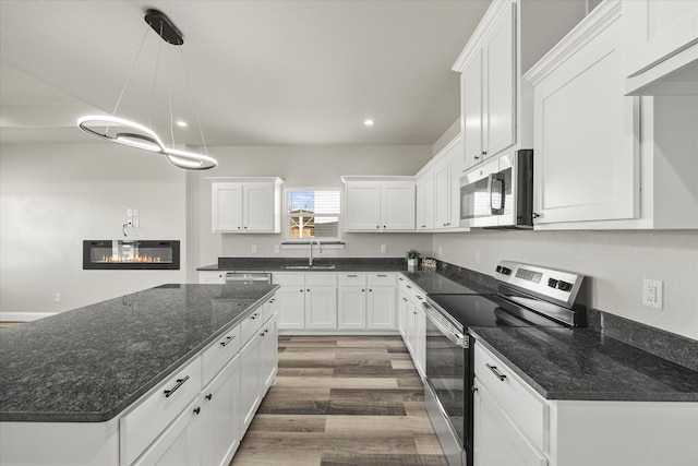 kitchen with sink, white cabinetry, decorative light fixtures, dark stone countertops, and appliances with stainless steel finishes