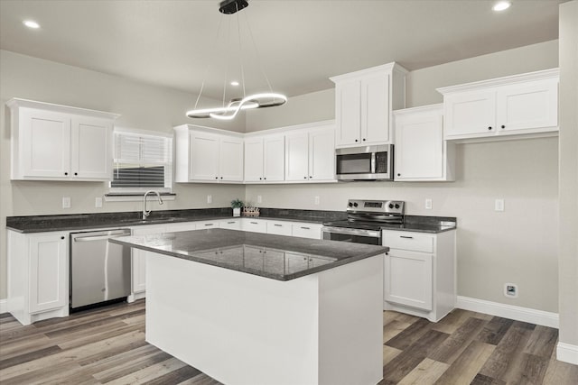 kitchen with white cabinetry, hanging light fixtures, a kitchen island, and appliances with stainless steel finishes