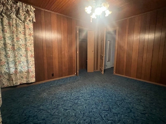 empty room featuring wood ceiling, carpet, and wood walls