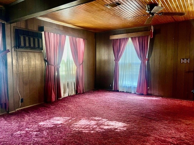 carpeted empty room featuring ceiling fan and wood walls