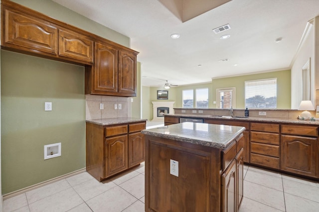 kitchen featuring light tile patterned flooring, a kitchen island, dishwasher, backsplash, and kitchen peninsula