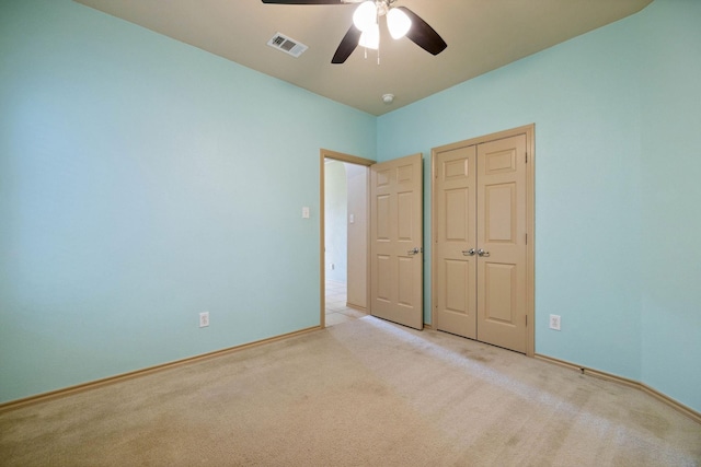 unfurnished bedroom featuring ceiling fan, light colored carpet, and a closet