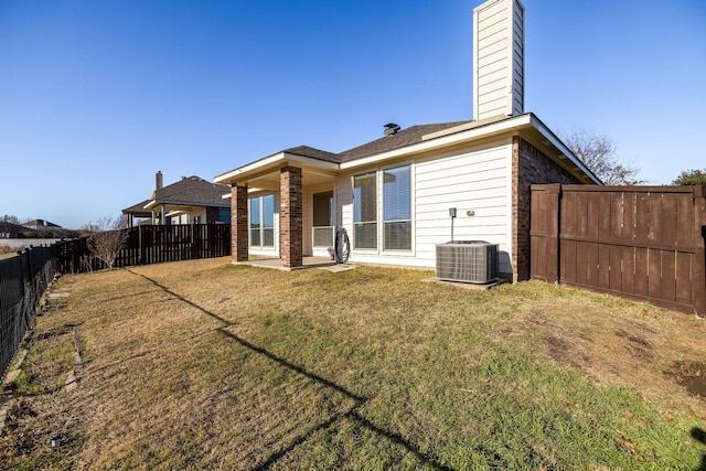 rear view of house featuring central AC unit and a lawn