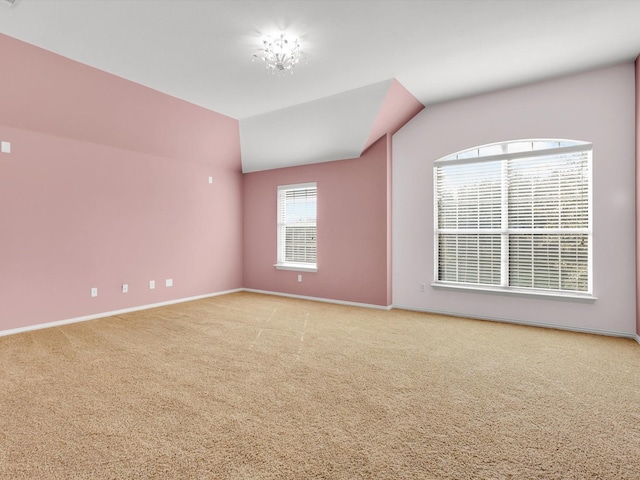 carpeted spare room featuring vaulted ceiling