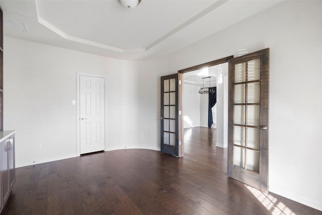 unfurnished room with dark hardwood / wood-style flooring, a tray ceiling, and french doors