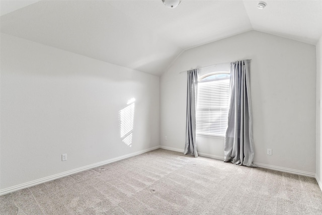 spare room featuring lofted ceiling and light colored carpet