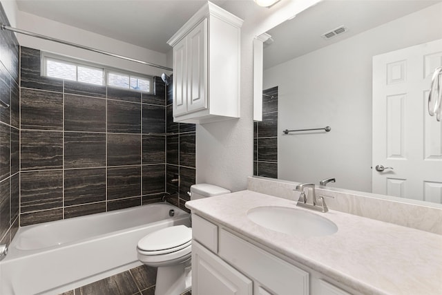 full bathroom featuring vanity, tiled shower / bath combo, and toilet