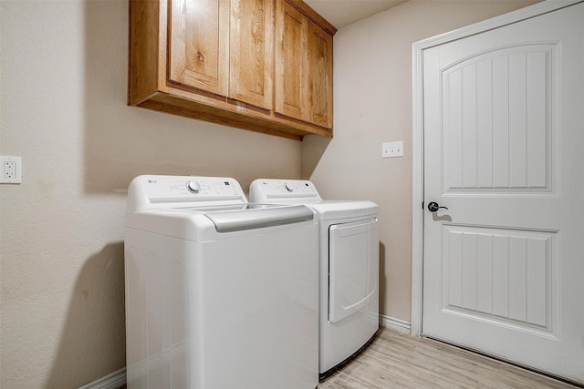 laundry area with cabinets, washer and dryer, and light wood-type flooring