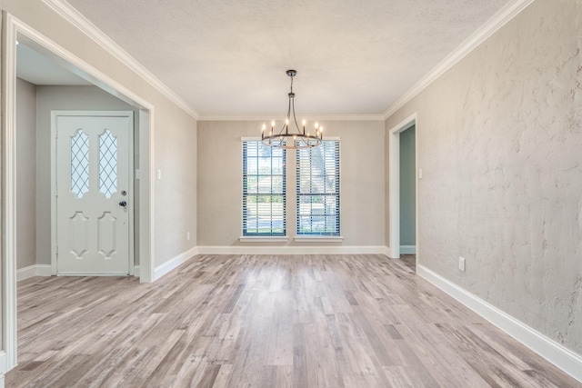 unfurnished dining area with a notable chandelier, ornamental molding, a textured ceiling, and light wood-type flooring